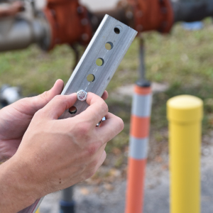 Omniflex ground-mount delineator installation showing lag bolt securing base for durable, long-term traffic safety.